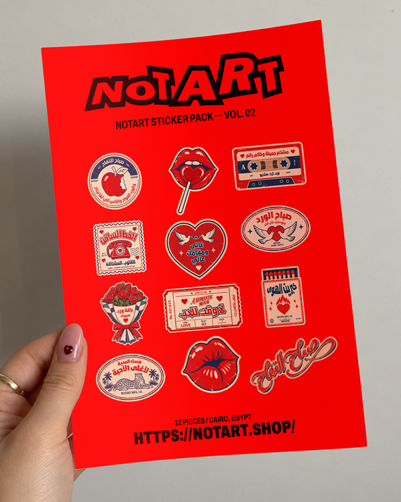 A hand holds a bright red sticker sheet featuring multiple illustrated stickers in red, black, white, and beige. The sheet includes Arabic text and designs such as lips, a cassette tape, a heart, roses, and cards.